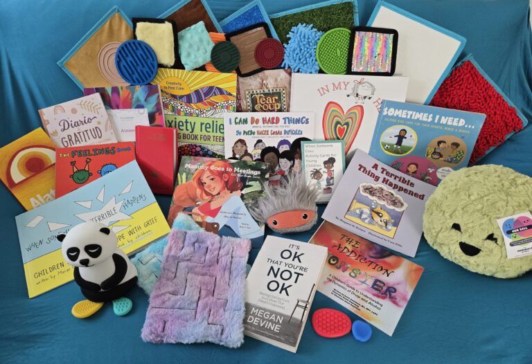 Books, stuffed animals, and other trauma support tools are spread out on display on a table.